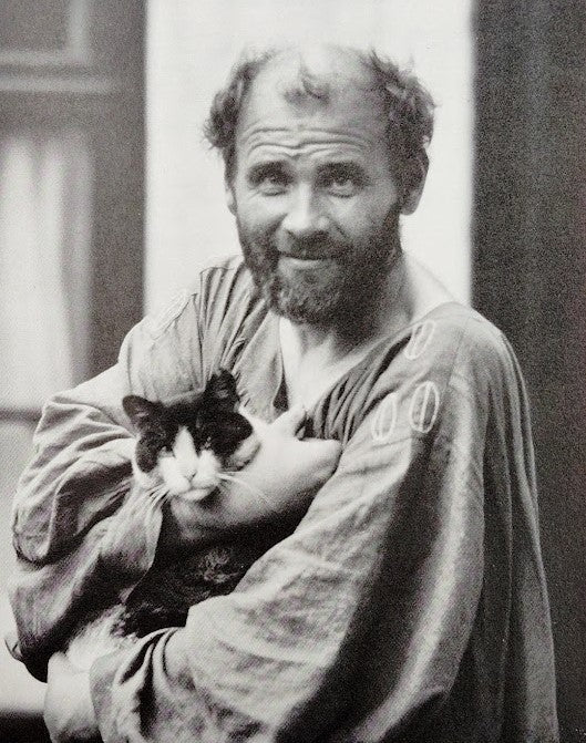 Gustav Klimt dans sa blouse de peintre avec un chat en 1912