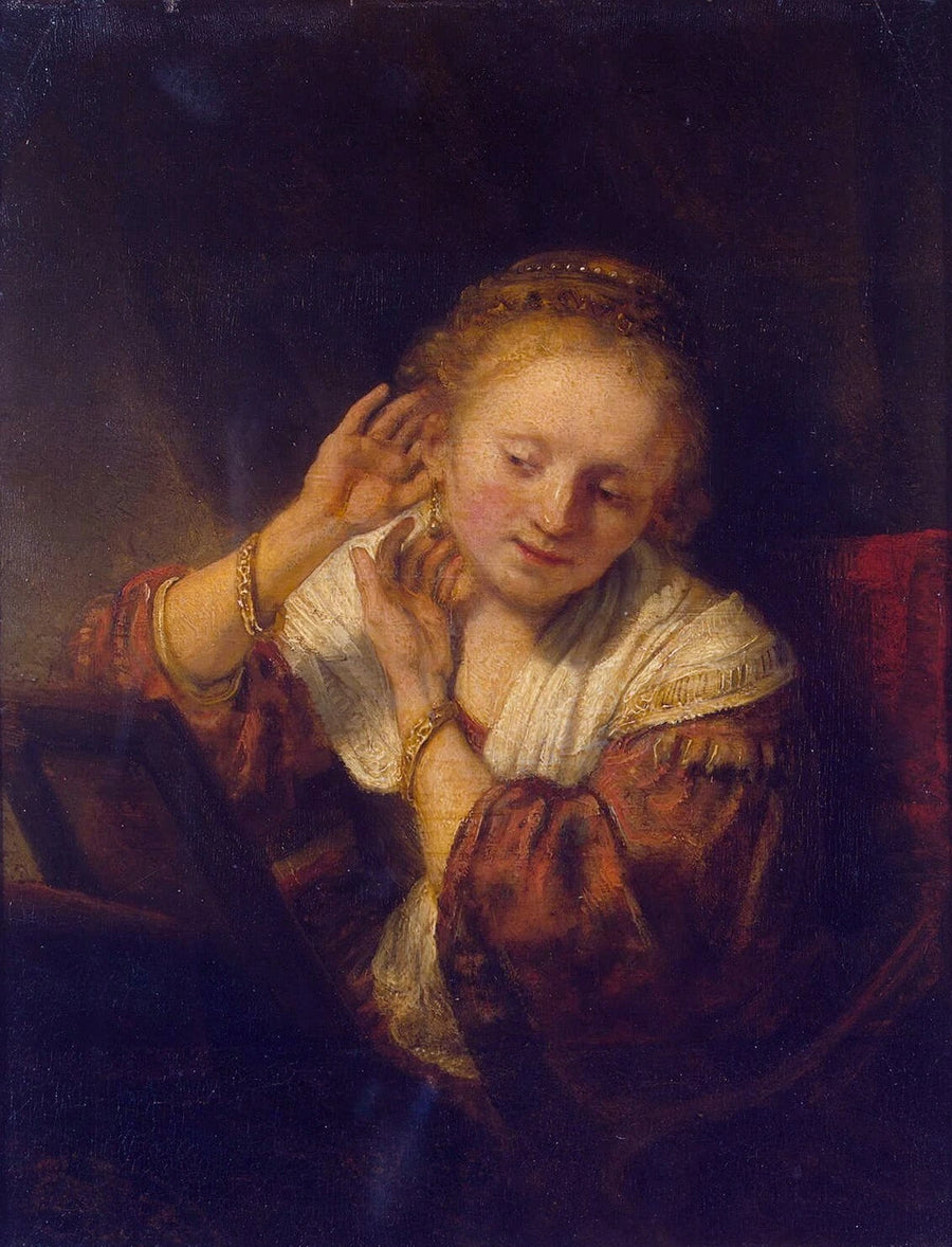 Jeune femme essayant des boucles d’oreilles – Rembrandt